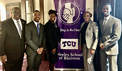 African American men and women in suits stand with the NABA banner.