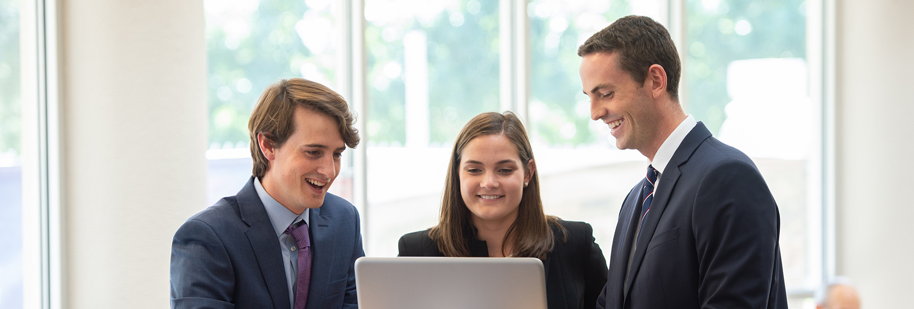 Section Image: Three students looking at a laptop 