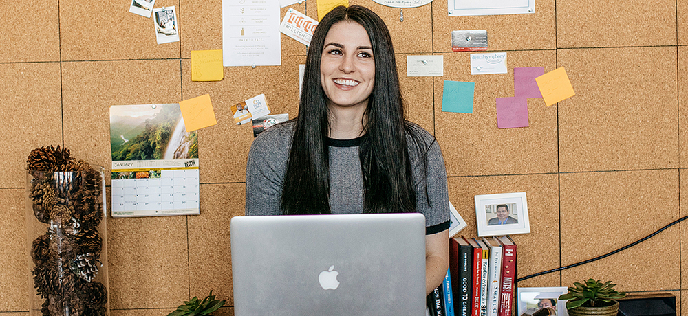 Section Image: Woman with laptop in front of bulletin board 