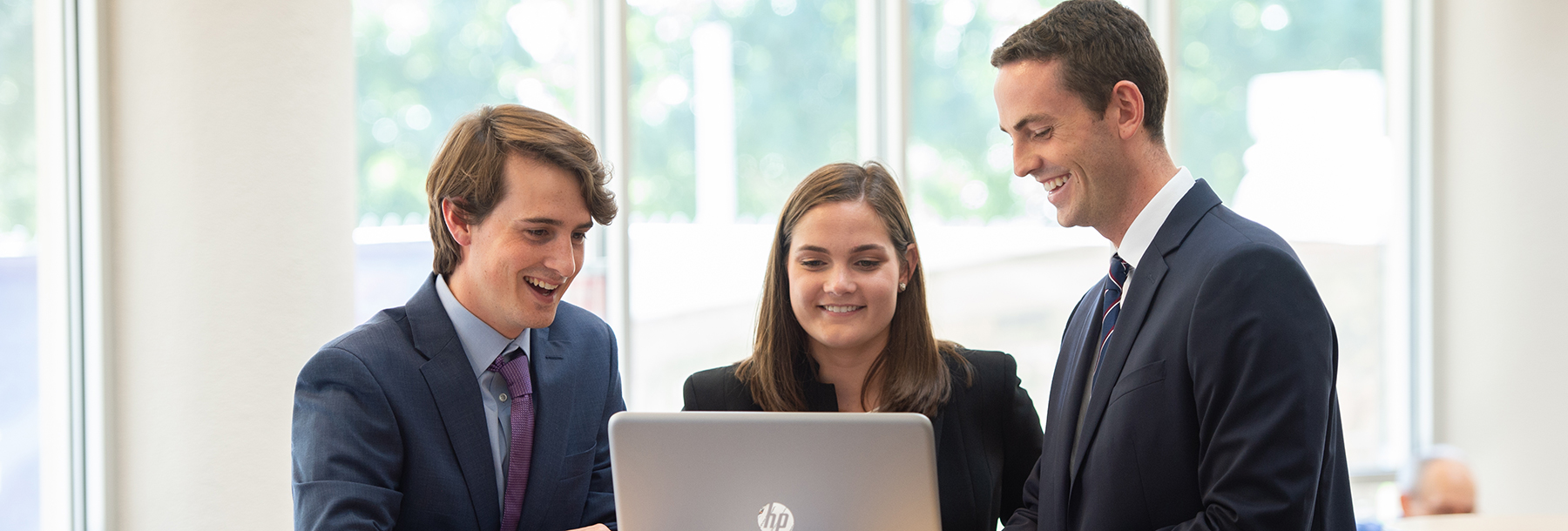 Section Image: three students at a laptop 