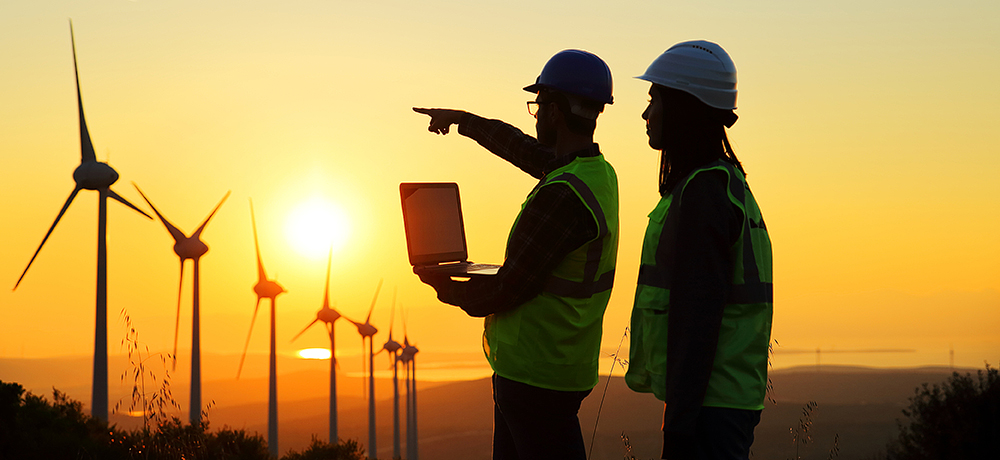 man and woman with laptop looking at windmills