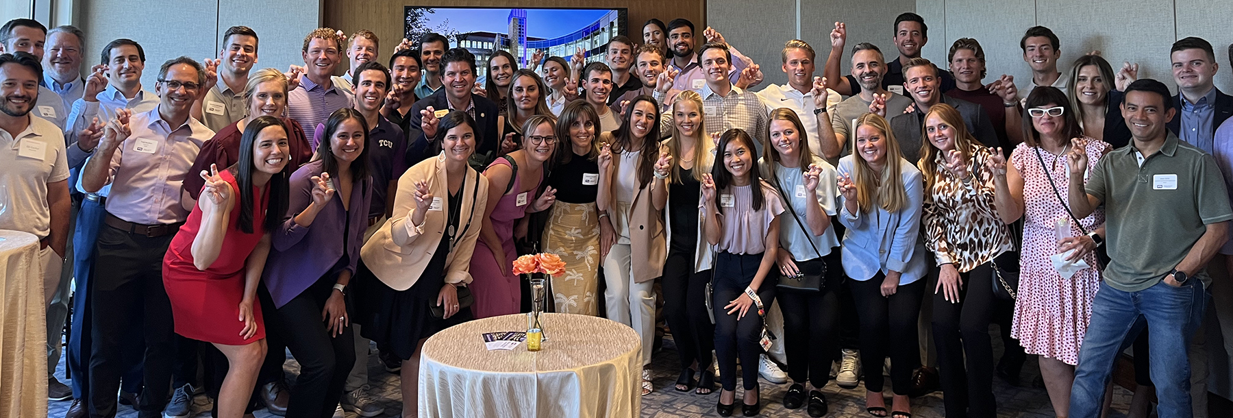 Section Image: Large group of alumni from Austin pose with Frogs Up with Dean Daniel Pullin. 