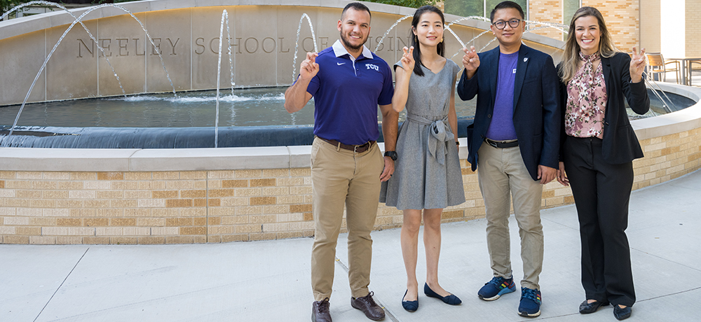 Section Image: Four MBA students with their frogs up at the Neeley Fountain 
