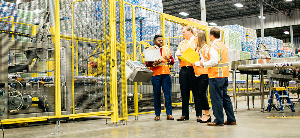 Section Image: People in orange vests with a laptop in a warehouse 