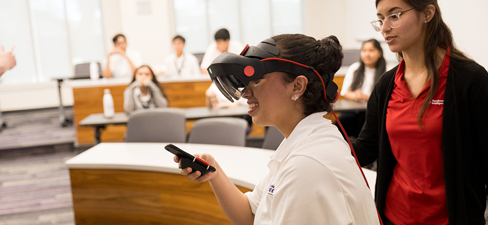 In a Neeley classroom, a student wears googles while holding a phone.