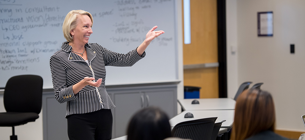 Section Image: Mary Uhl-Bien at the white board while teaching 
