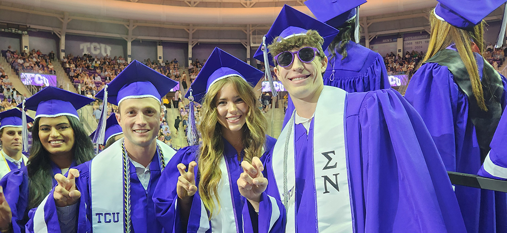 Section Image: Graduates take pictures in cap and gown with family outside of Schollmaier Arena 