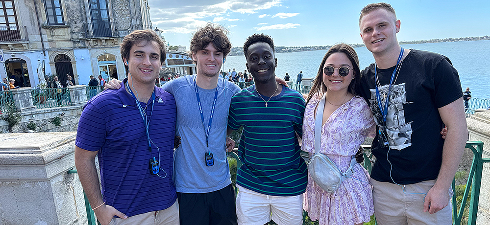 Section Image: 5 students on a study abroad trip pose before a view of the ocean 