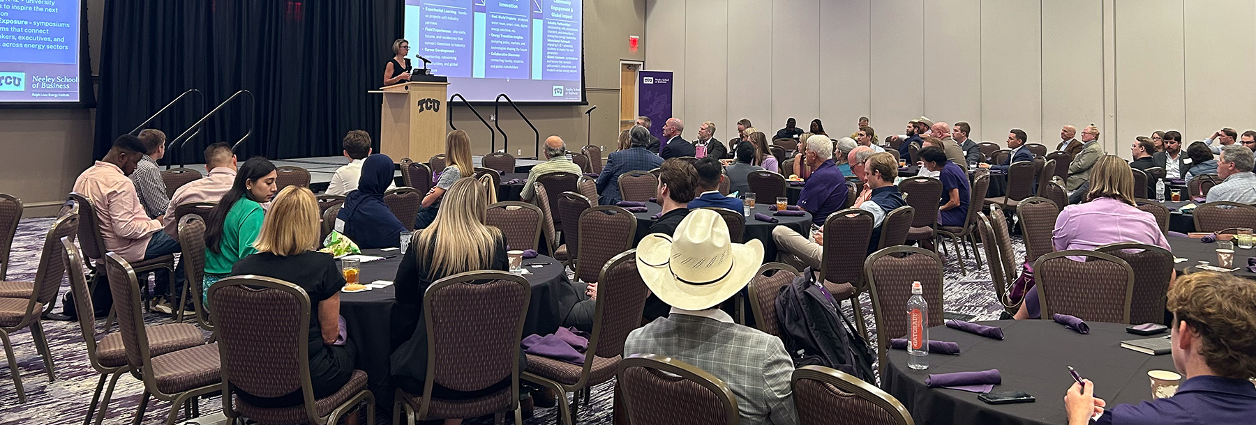 Section Image: BLUU Ballroom with speaker on stage and audience at round tables 