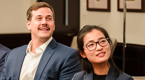 Male and female student at a conference table looking intently