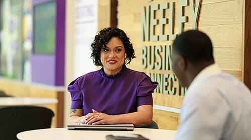 A man and a woman sitting at a round table in the Hays Business Commons