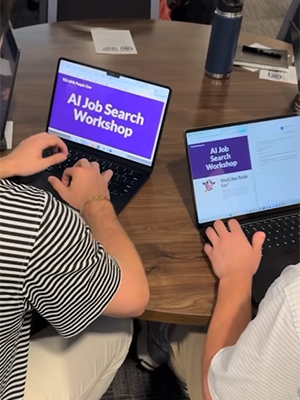Two students sitting at the table with laptops open to AI job search workshop