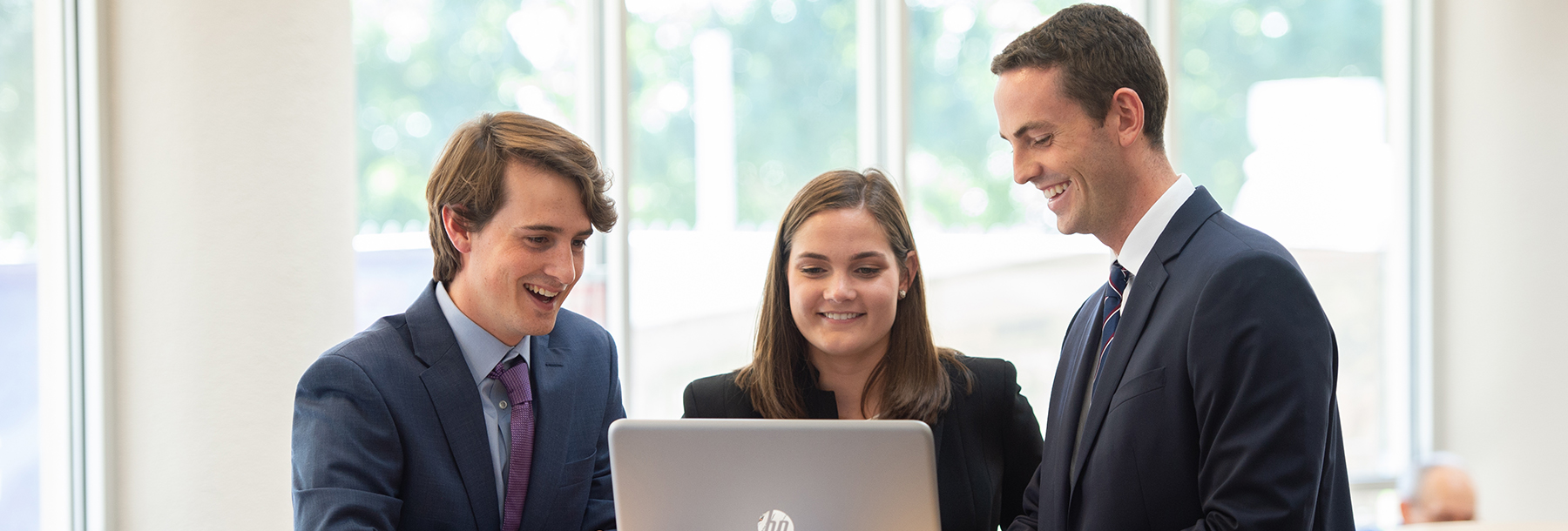 Section Image: Three students looking at a laptop. 