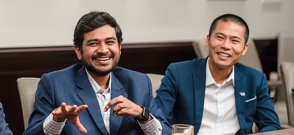 Section Image: Two international students in suits at a conference table 