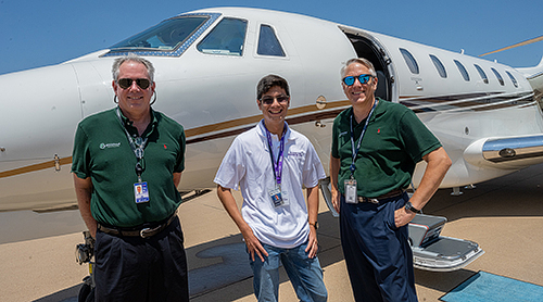 A student and two adults in front of a small jet