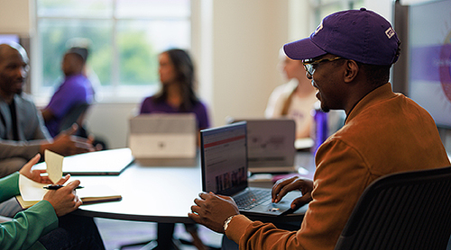 Student in TCU hat with a laptop in a smart classroom