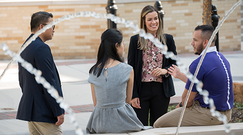 Four MBA students with their frogs up at the Neeley Fountain 
