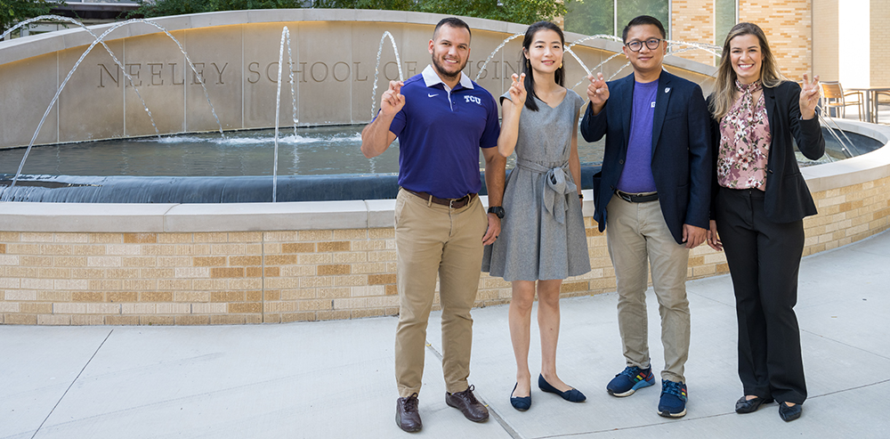 Four students standing in front of the Neeley fountain