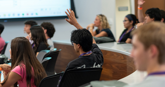 High school student raising hand during a Neeley pre-college program