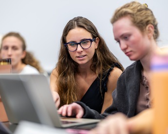 Student assisting another student with a business school assignment